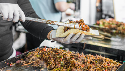 Chef handing a taco to a foodie at a street food market