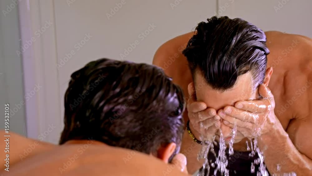 Athletic man washing his face after shaving.