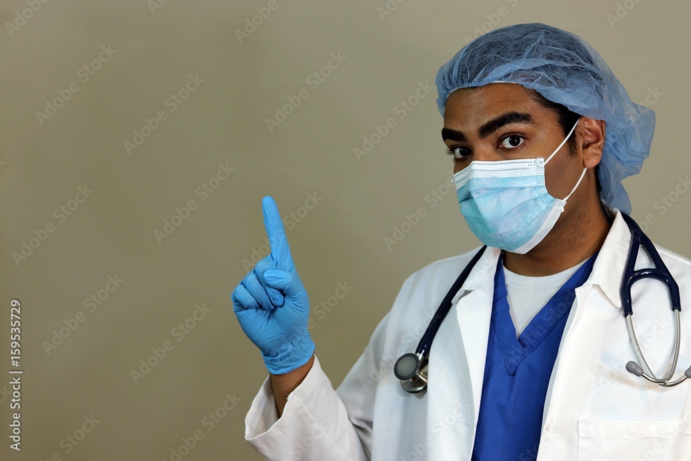 Young handsome doctor in blue scrubs pointing up Young handsome doctor in blue scrubs pointing up
