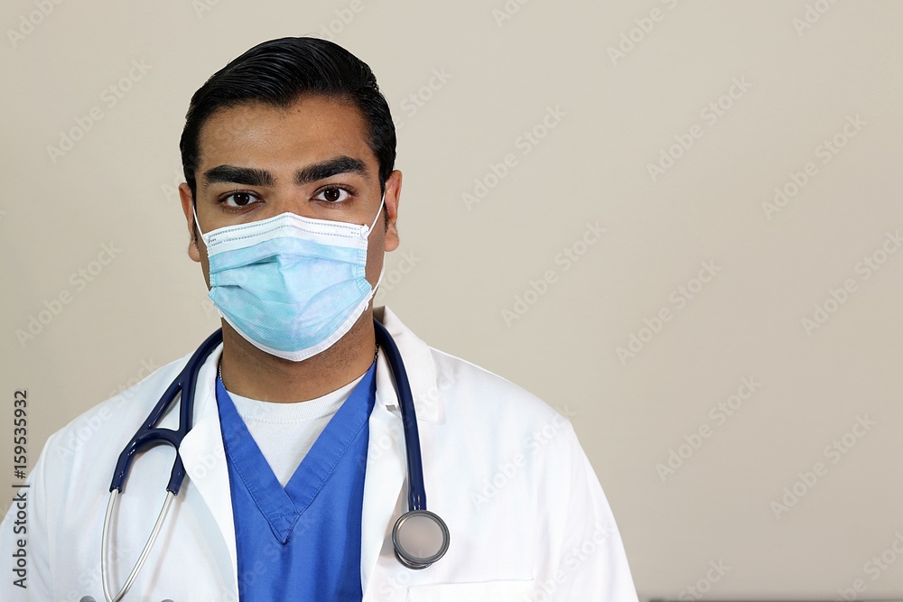 Young handsome doctor in blue scrubs and white lab coat and face mask Young handsome doctor in blue scrubs and white lab coat and face mask