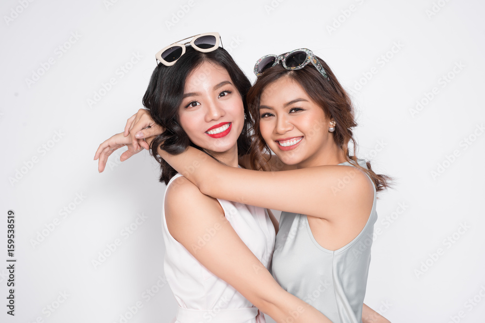Two fashionable women in nice dresses standing together and having fun