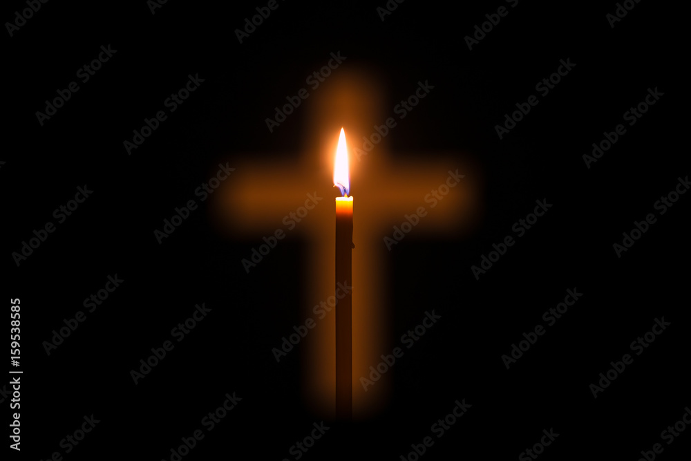 Fototapeta premium Candle is glowing through hole in shape of Christian cross