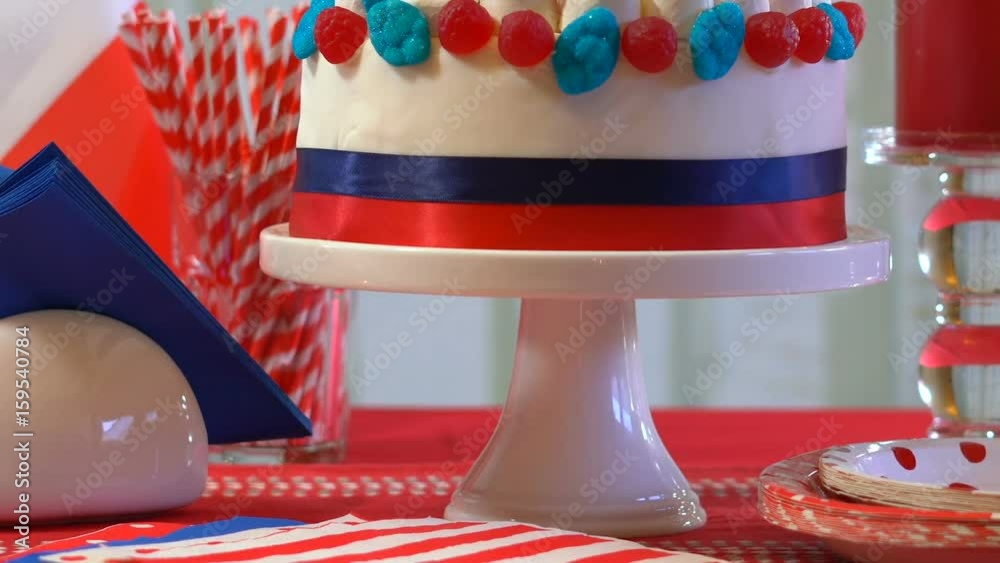France Bastille Day celebration party table with showstopper cake decorated with candy, stars and flag, panning across and up.