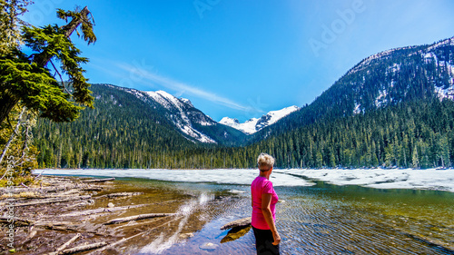 Woman enjoying the view of the partly frozen Lower Joffre Lake and the Matier Glacier in the Coast Mountain Range along the Duffey Lake Road, between Pemberton and Lillooet in British Columbia