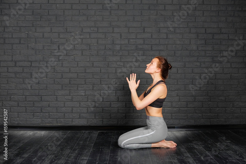 Healthy lifestyle. The girl is practicing meditation in yoga class. Relaxation and Stretching. Уoung slim sporty girl holds her hands over head in Namaste posture! Woman do yoga indoors.
