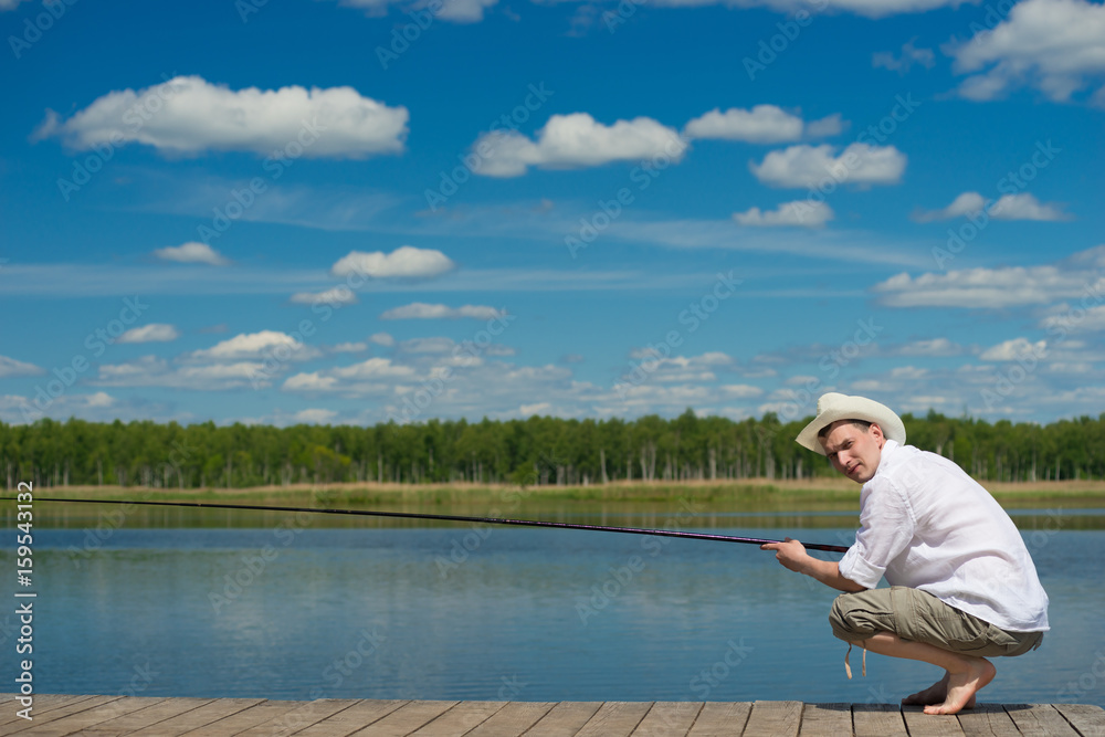 man in a hat and a white shirt, is fishing on the lake