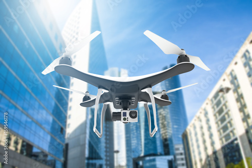 Drone with digital camera flying in a modern city with sunlight