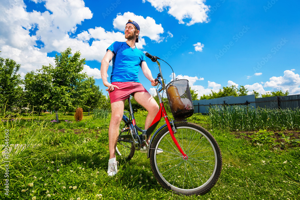 Happy man is sitting on bicycle at green summer countryside background.