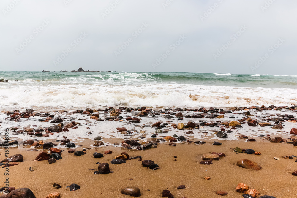 Coast, waves and beach with yellow sand and pebbles