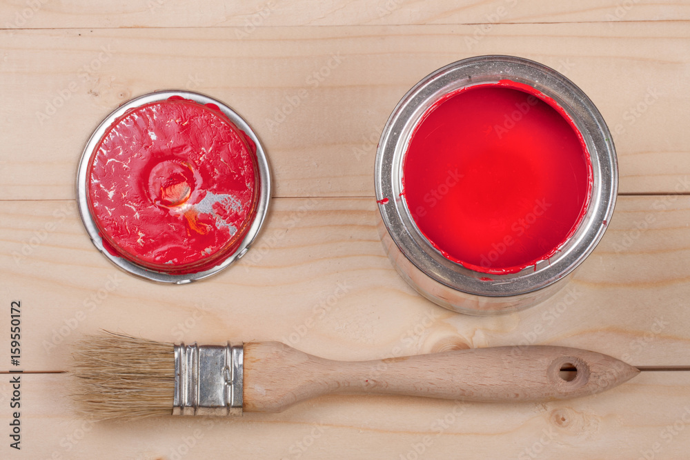 Φωτογραφία red paint in the bank to repair and brush on the light wooden background