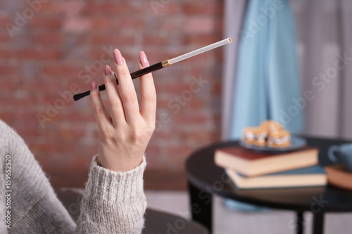 Female hand with cigarette holder on blurred background