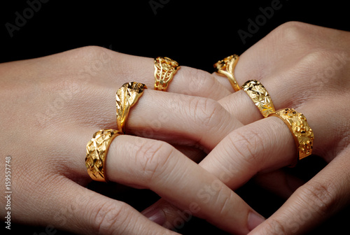 woman's hand with many jewelry rings on black background