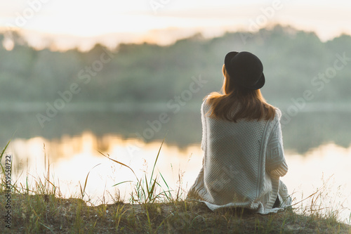 Fototapeta A girl sitting on the river bank in silence