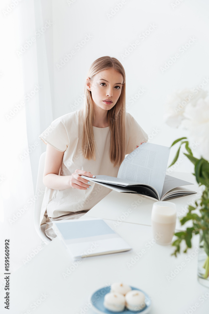 Woman sitting indoors reading book. Looking at camera. Woman sitting indoors reading book. Looking at camera.
