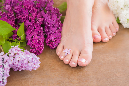Young woman's feet. Smooth skin. Spring and summer atmosphere with fresh, fragrant lilac flowers.
