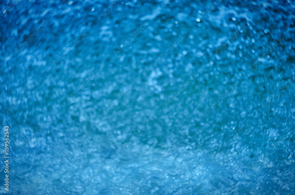 Blurred natural background of blue water with bokeh and sun reflections
