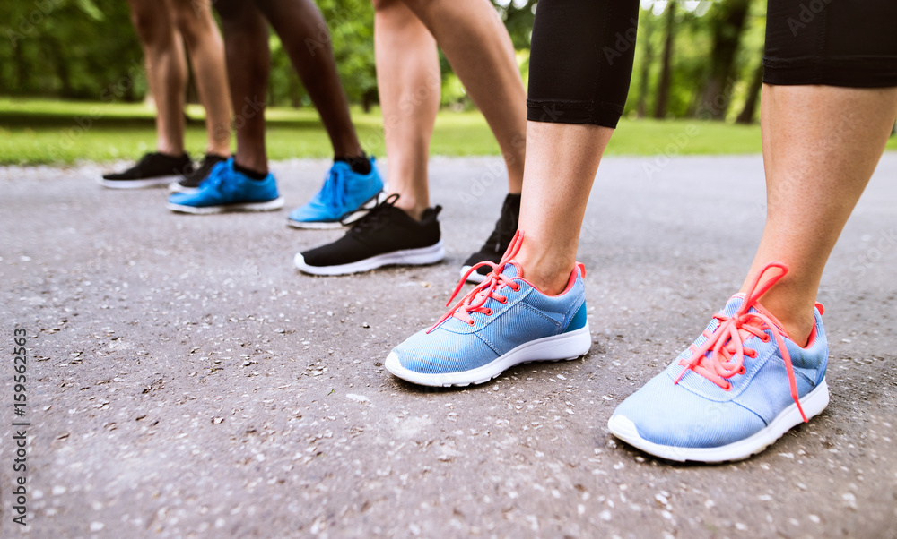 Legs of young athletes prepared for run in green sunny park.