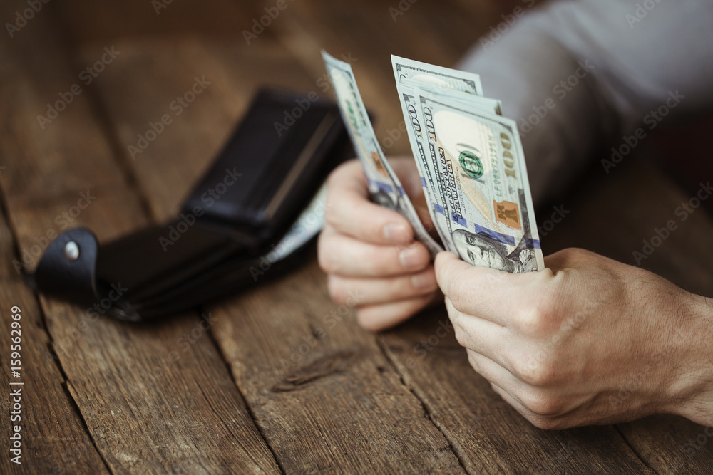 Male hands holding dollar banknote on old wooden background Male hands holding dollar banknote on old wooden background