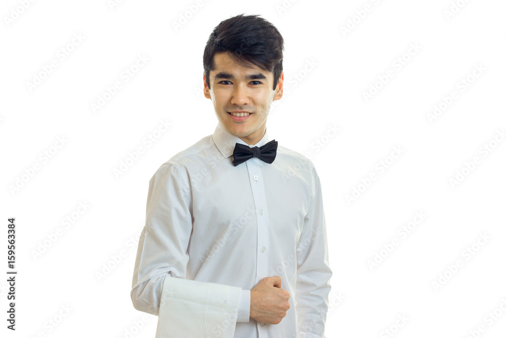 Cheerful young man waiter in uniform with bowtie smiling on camera Cheerful young man waiter in uniform with bowtie smiling on camera