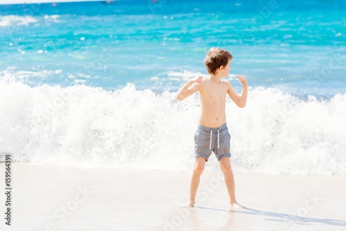 Little boy playing at the beach. Happy summer vacations.