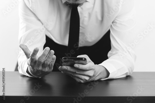 close up of businessman working with smart phone on wooden desk in modern office