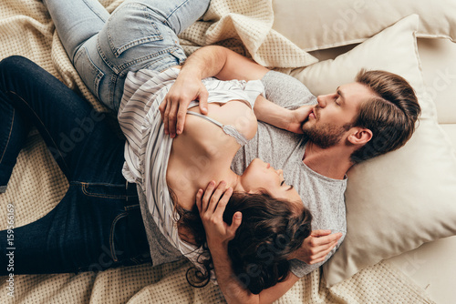 Foto High angle view of beautiful young couple in love hugging while lying on bed