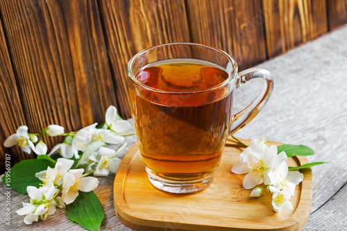 A cup of tea with jasmine flowers on brown wooden background