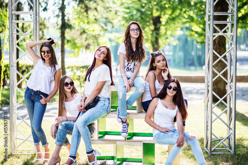 Six wonderful model girls posing on wooden boxes in the park on a sunny day.