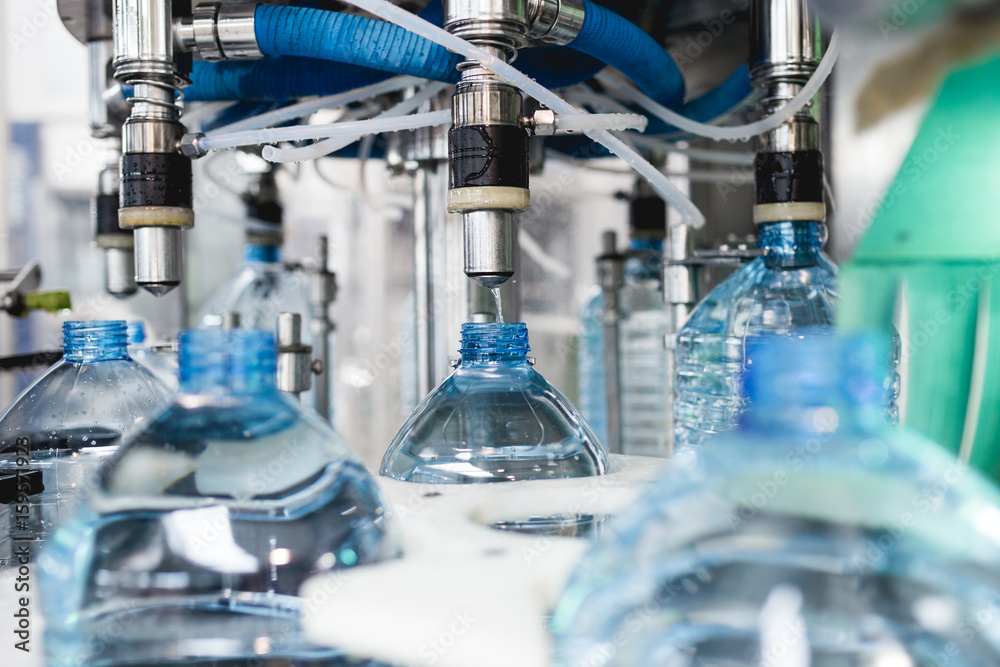 Industrial factory indoors and machinery. Robotic factory line for processing and bottling of pure spring water into canisters and bottles. Selective focus. Short depth of field. Industrial factory indoors and machinery. Robotic factory line for processing and bottling of pure spring water into canisters and bottles. Selective focus. Short depth of field.