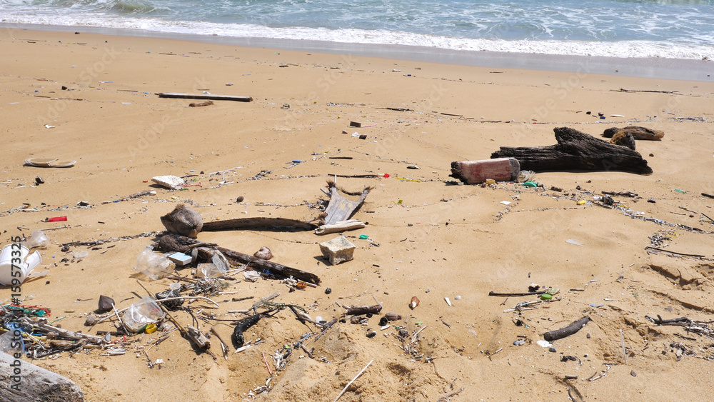 Obraz premium Pollution on the beach of tropical sea. Plastic garbage, foam, wood and dirty waste on beach in summer day.