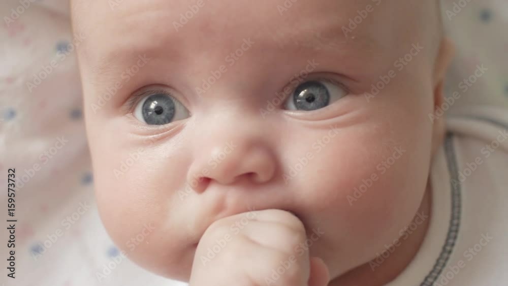 A cute little baby is looking into the camera and is wearing a white hat. The baby looks around and then smiles and laughs. A cute little baby is looking into the camera and is wearing a white hat. The baby looks around and then smiles and laughs.