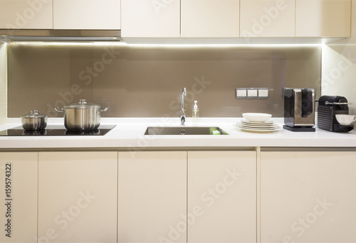 Arranged kitchen pot, plates and kitchen appliance on kitchen cabinet