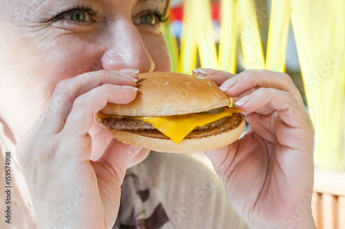 the girl eats an appetizing cheeseburger