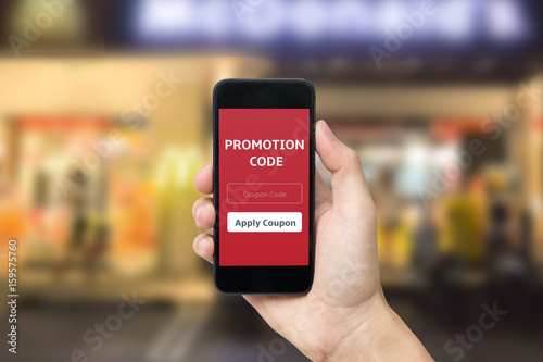 hand holding smart phone with promotion code application on mobile screen.