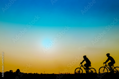 Silhouette of cyclists riding   bikes  on road at sunset. © Pattadis