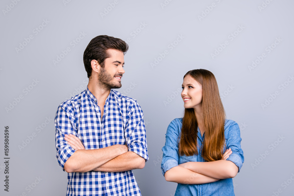 Love, trust, friendship, fun, happiness. Two cheerful young lovers are looking at each other and smile, wearing casual clothes, with crossed hands on the pure background Love, trust, friendship, fun, happiness. Two cheerful young lovers are looking at each other and smile, wearing casual clothes, with crossed hands on the pure background