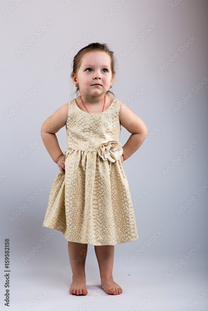 Little girl in dress poses on grey background Little girl in dress poses on grey background