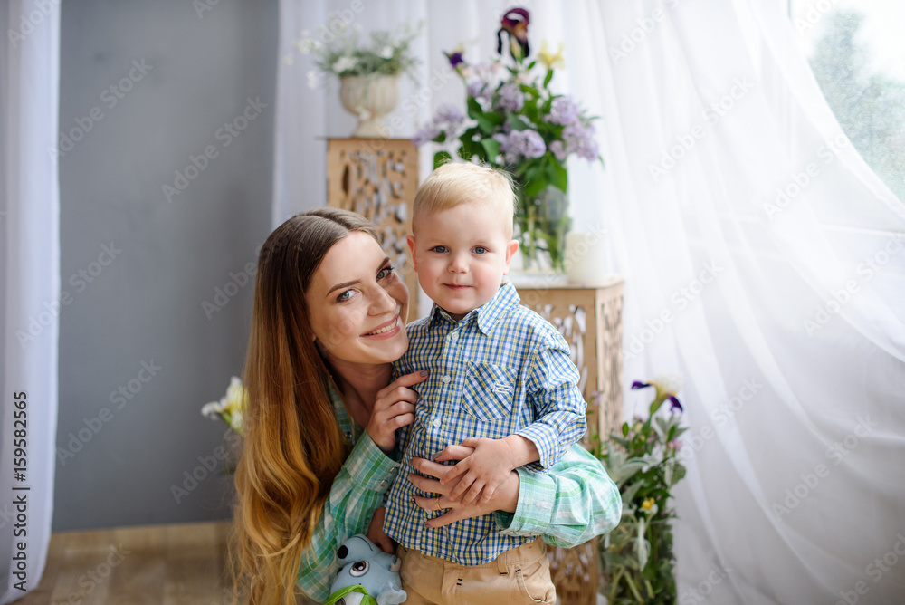 Portrait of cute kid boy hugging his mother at home. Happy family. Mum and son smiling and hugging Portrait of cute kid boy hugging his mother at home. Happy family. Mum and son smiling and hugging