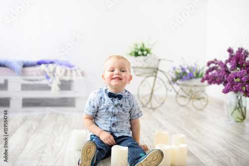 Portrait of attractive laughing blonde little boy posing at home