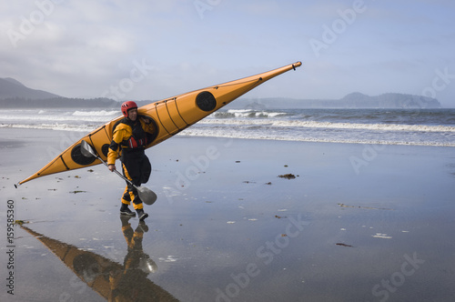 Man carrying kayak on Hobuck Beach, Makah Bay, Washington, USA photo