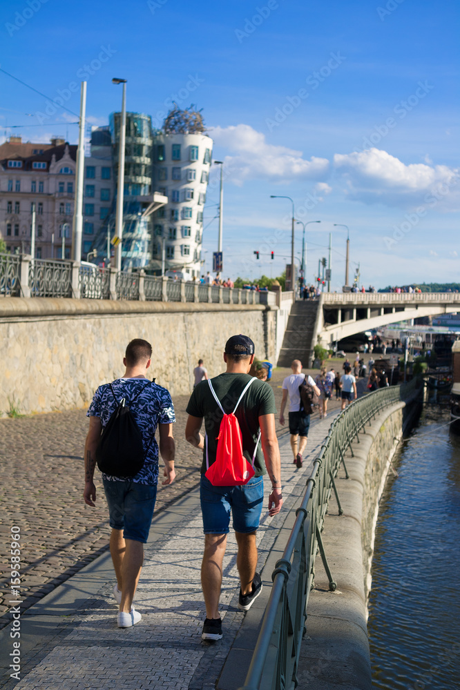 Samolepka Naplavka - riverfront and embankment of Vltava River, Prague, Czech Republic - pedestrians, tourists and locals are walking on paved pavement riverside