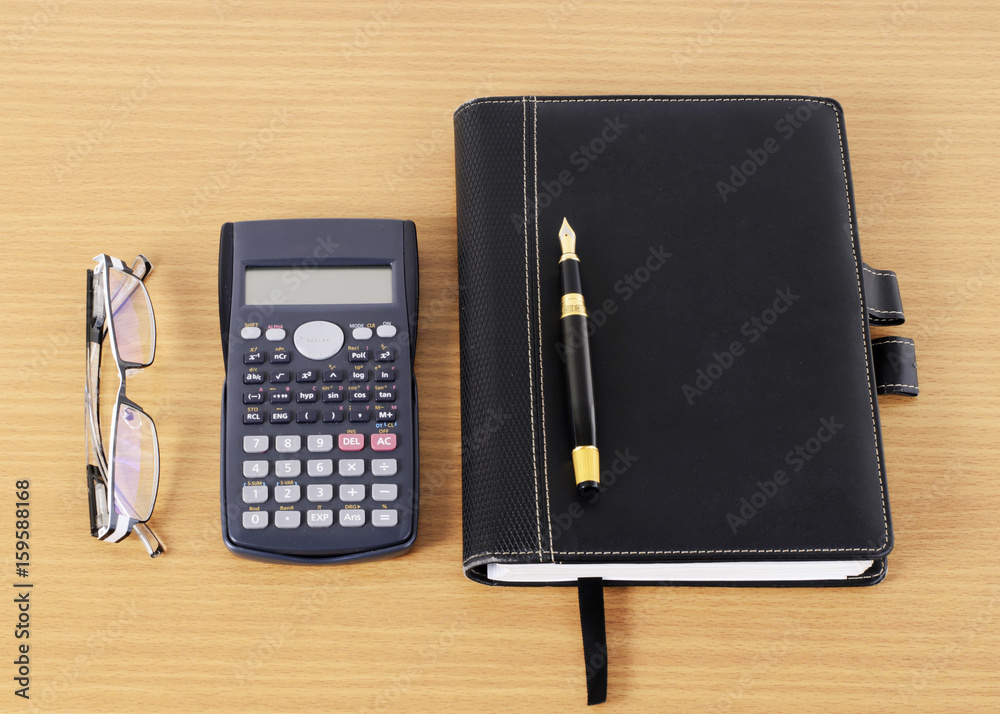 Fountain Pen and Business books and calculator and eyeglasses on wooden desk for office work place concept