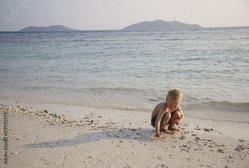 Boy playing in sand on beach, Rawa Island Malaysia photo