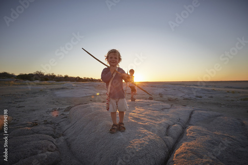 Portrait of young boy standing on rock, holding spear, sunset, Gweta, makgadikgadi, Botswana photo