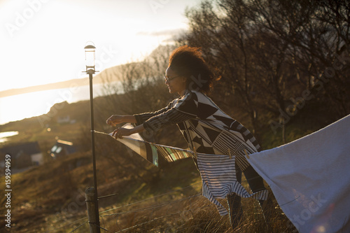 Woman hanging out washing in garden, Tokavaig, Isle of Skye, Scotland photo