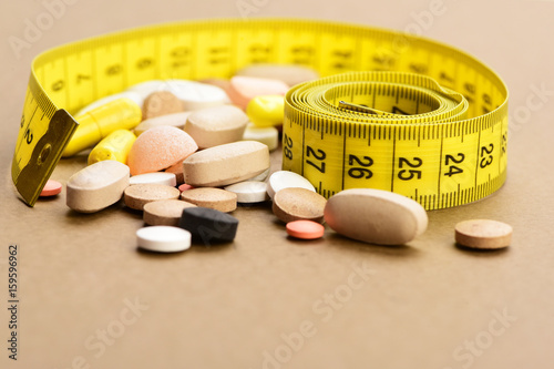 Tablets and tape for measuring on beige surface, close up