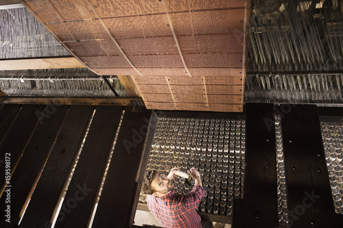 Overhead view of male weaver using old weaving machine in textile mill