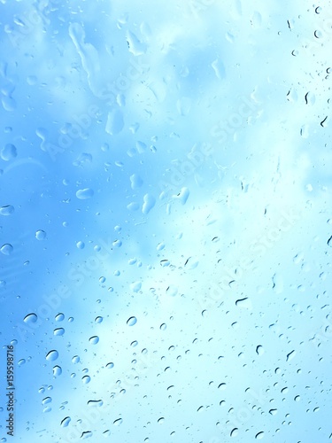 Rain drops on a mirror look through blue sky background.