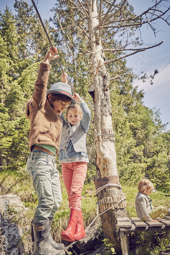 Two children walking across single rope bridge photo