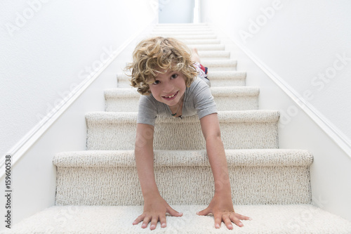 Portrait of boy crawling headfirst down stairs